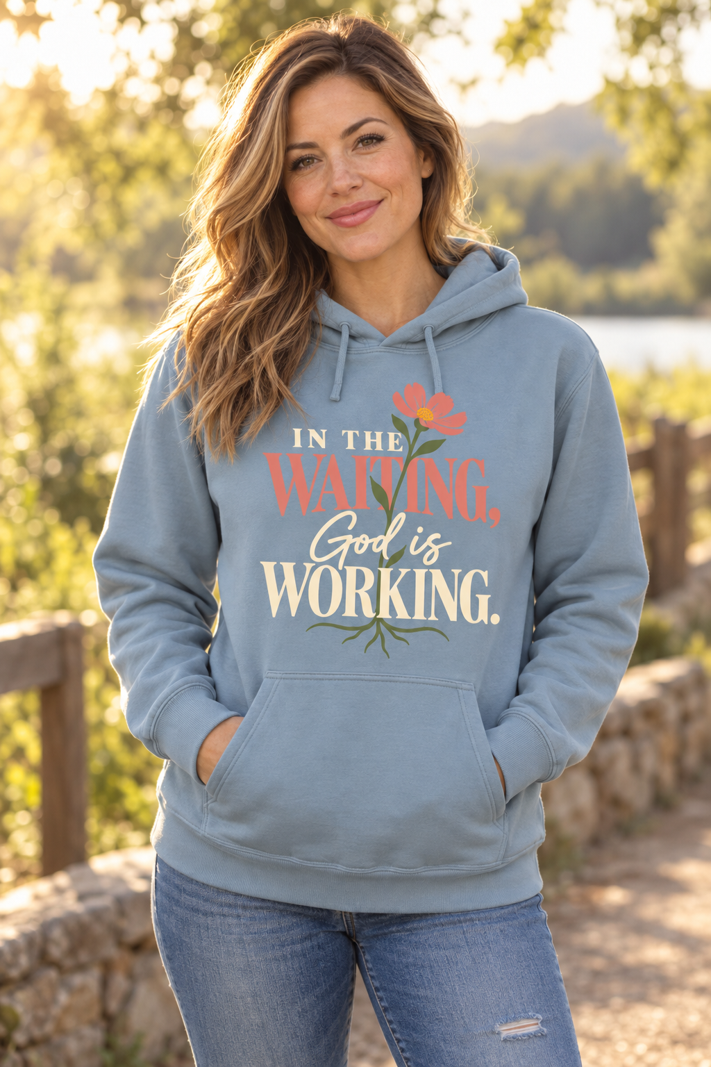 Woman wearing the Stone Blue In the Waiting, God Is Working hoodie outdoors