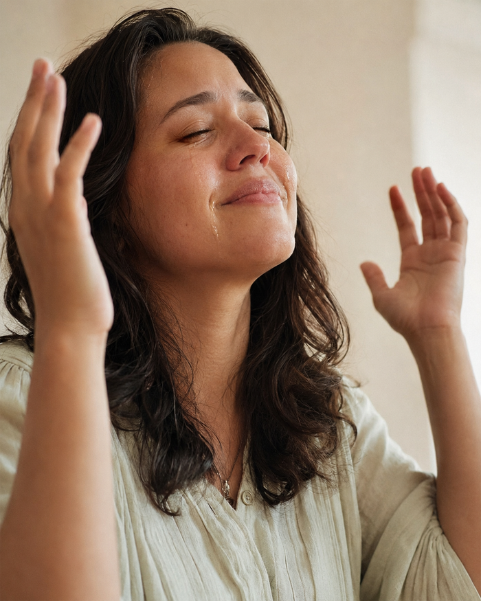A woman moved to joyful tears in prayer, hands lifted