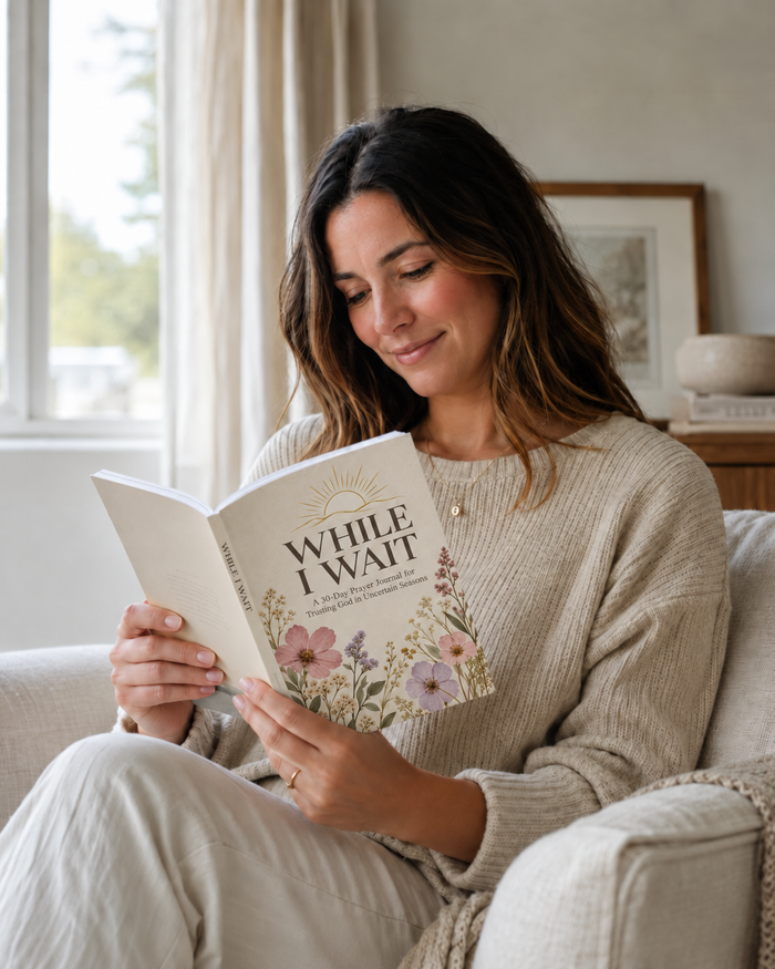 A woman relaxing at home reading the While I Wait journal